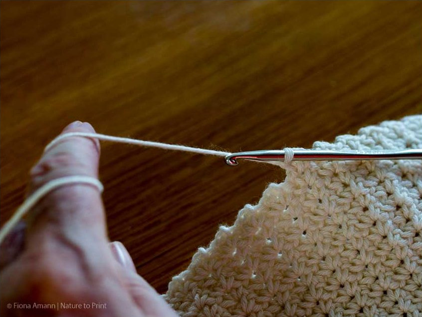 Jedes Maschenpäckchen schließt mit einer zweiten festen Masche Gehäkeltes Plaid im Wölkchenmuster: Das Maschenpäckchen endet mit einer weiteren festen Masche